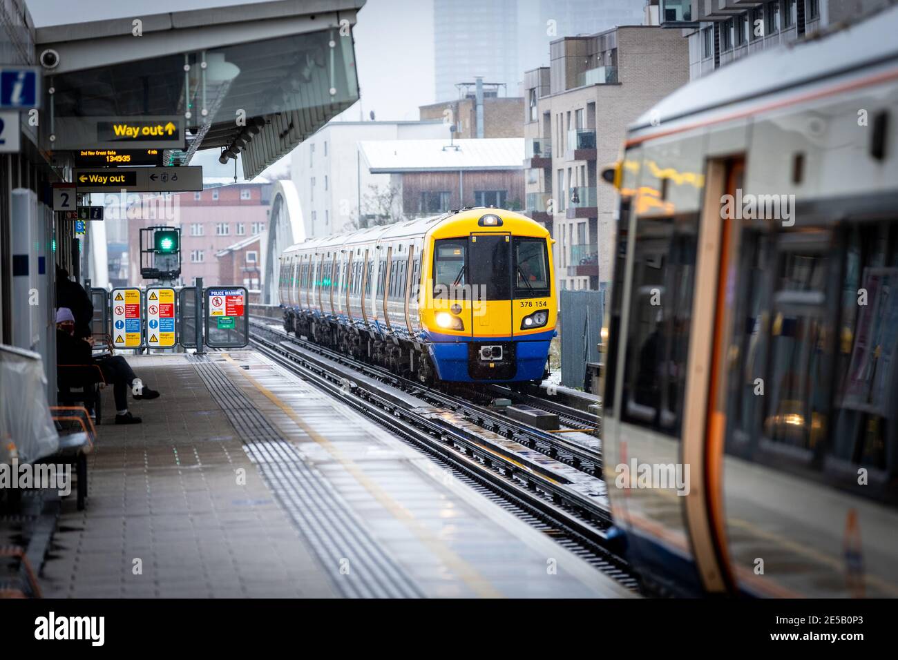 A Overground train approaches Haggerston station on a cold snowy day. Stock Photo