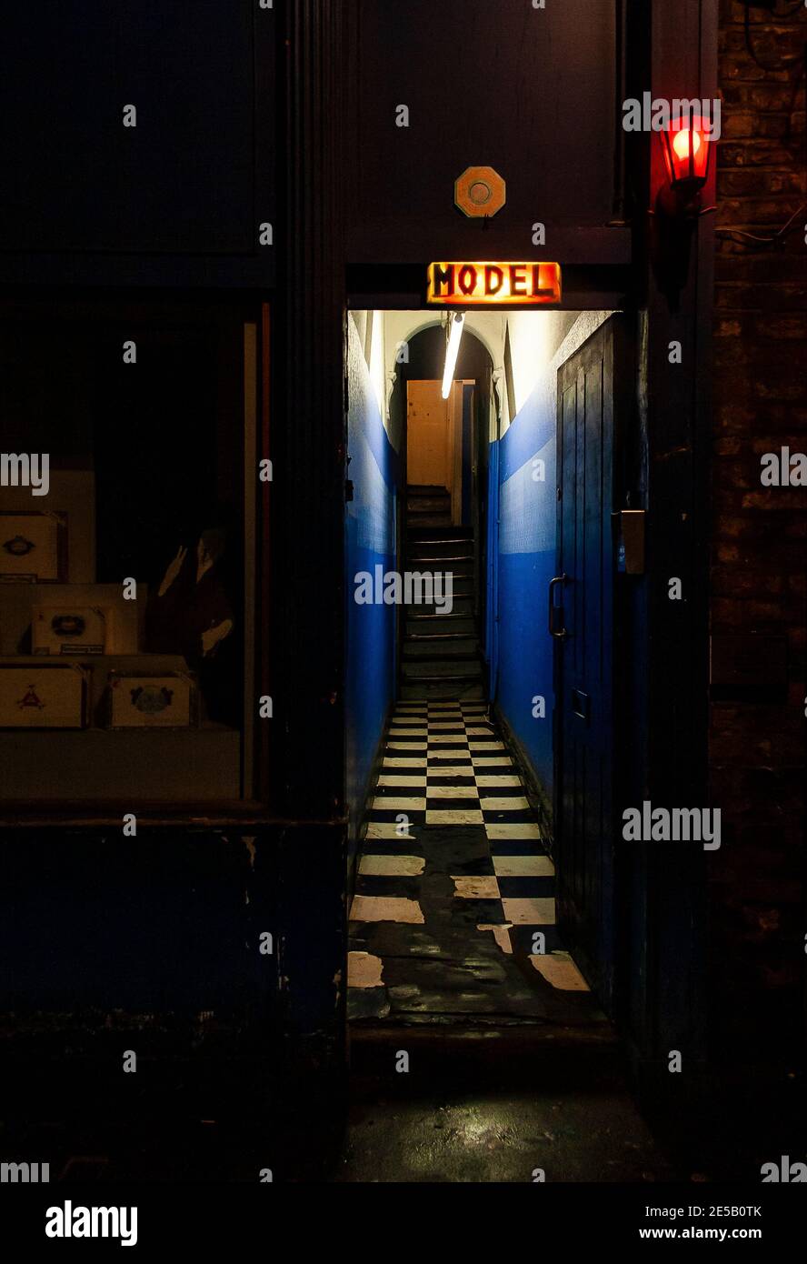 Entrance to a brothel in red light district in Soho London with illuminated signage advertising 'model' Stock Photo