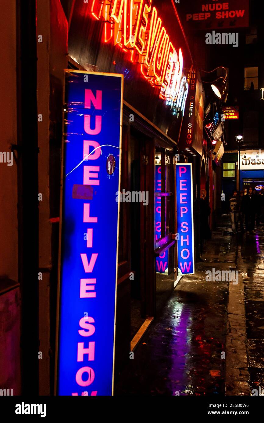 Red light district in Soho London at night with illuminated signage advertising nude live show and peep show Stock Photo