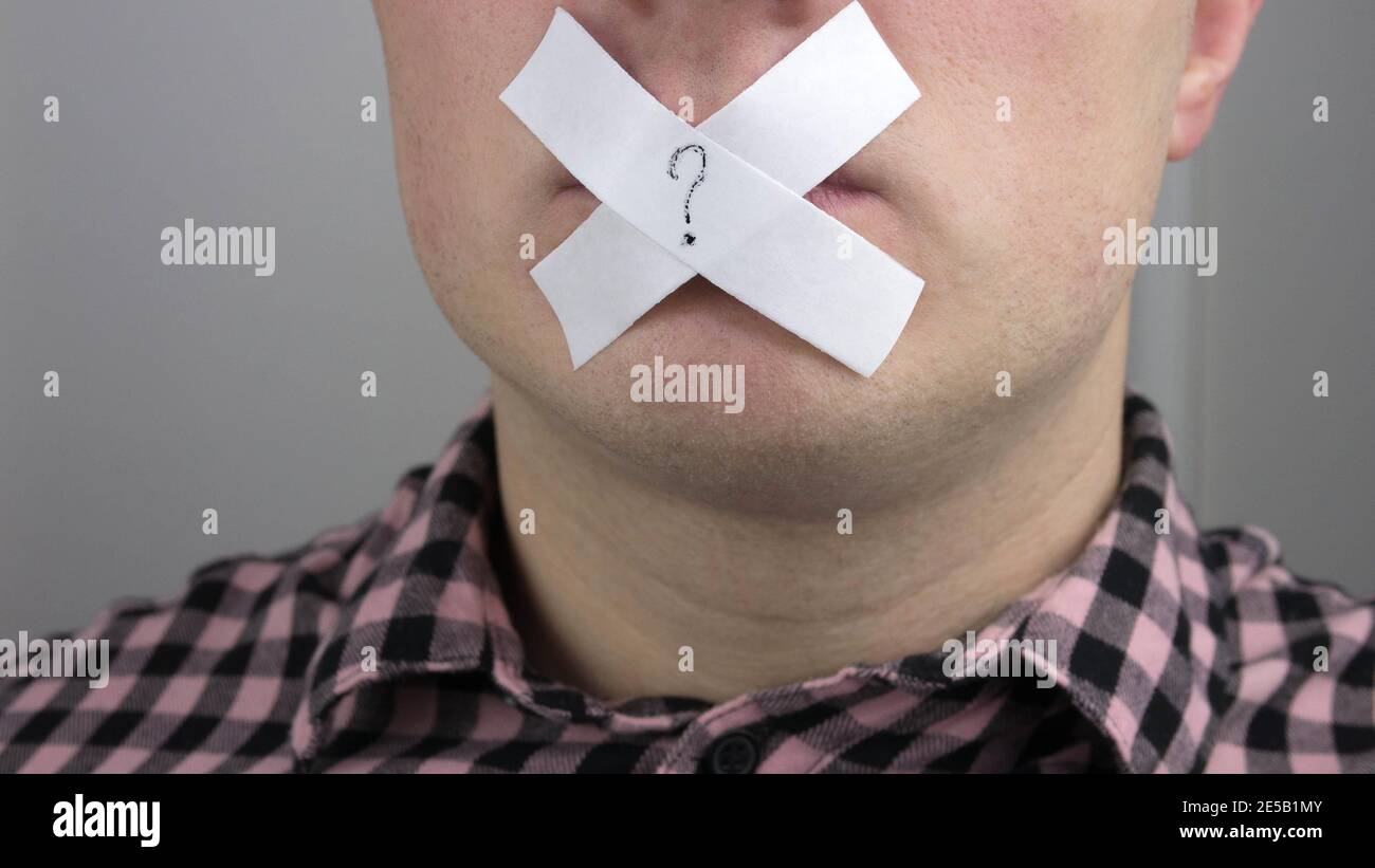 A question mark on a man's lips, a man with a sticky tape sealed his mouth, a man covered his mouth with a leuco plaster. Stock Photo