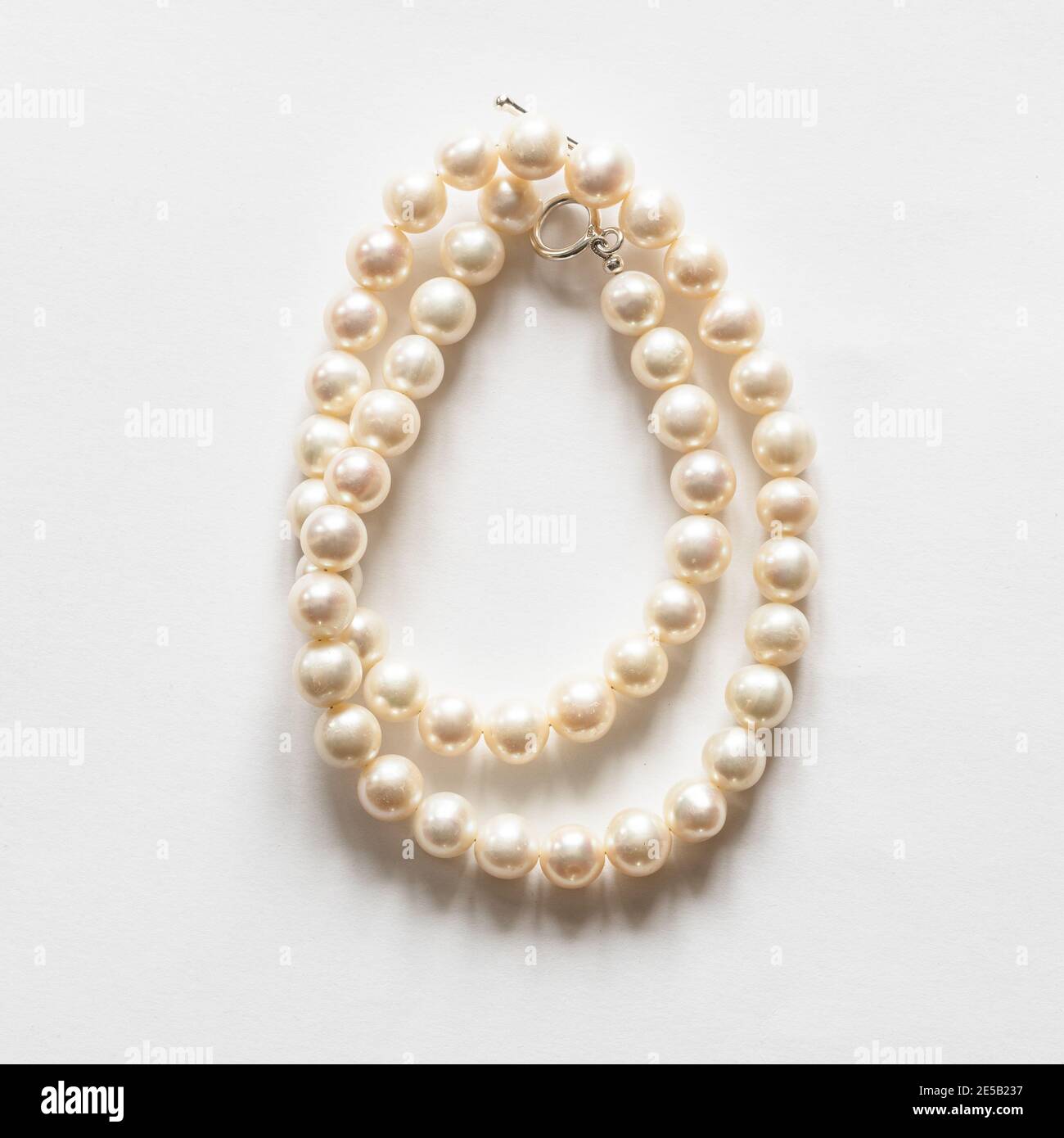 folded natural white pearl necklace on white background Stock Photo