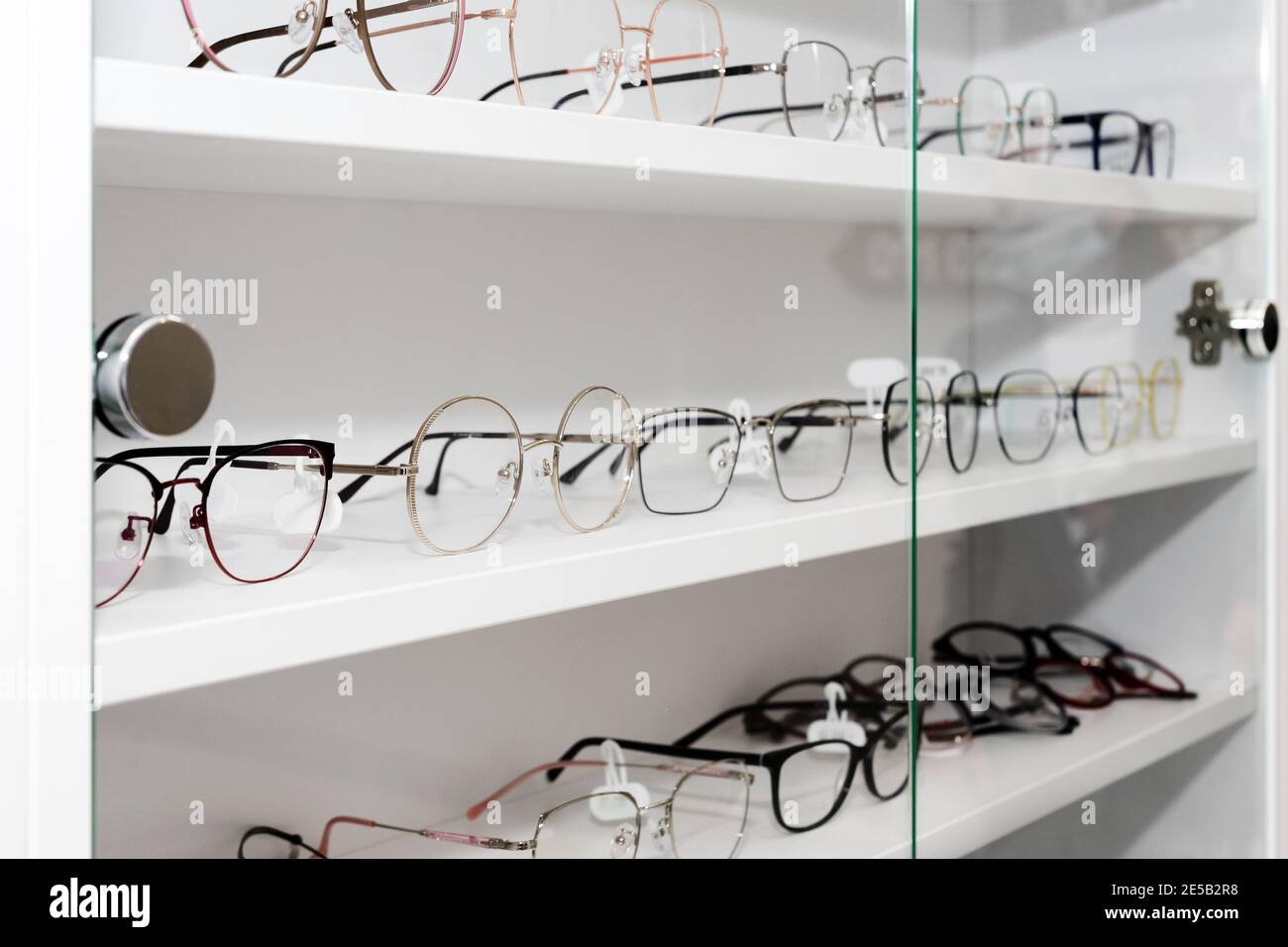 Eyeglasses in optical store, fashion, different glasses on white shelf in shopping mall