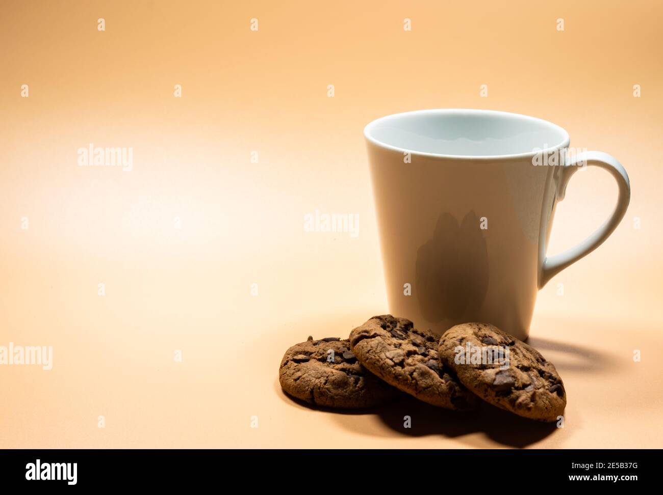 Close up white mug of milk and pile of dark chocolate chip cookies Stock Photo