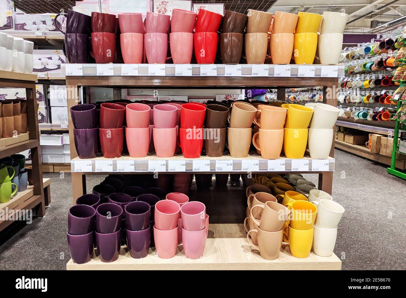 Сups are sold at the shop. Rows of different multi-colored cups for home on shelves in a supermarket. Stock Photo