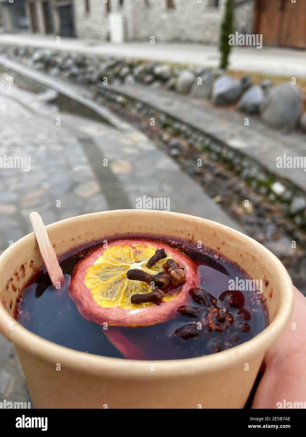 Glass of red mulled wine with spices and fruits drunk on the street. Stock Photo