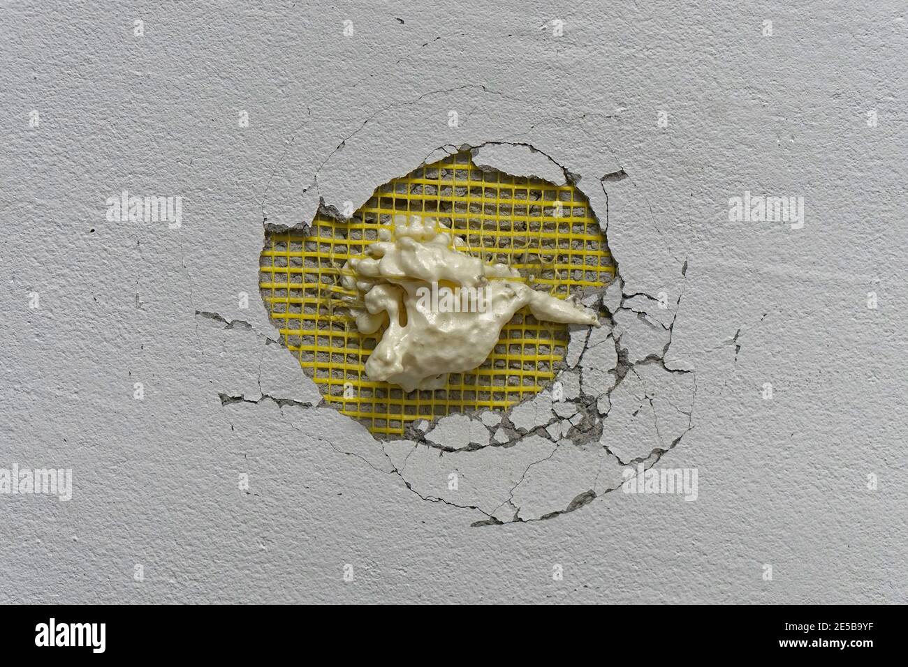 Big hole in wall with expanded foam repair try Stock Photo Alamy