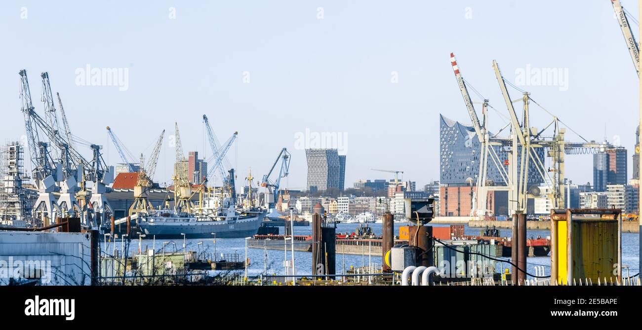25 December 2020, Hamburg: Historic cranes of the Hamburg Harbour Museum, the Dancing Towers of the Reeperbahn and the Elbe Philharmonic Hall behind container cranes of the Hansa Harbour form the skyline of the Hanseatic City of Hamburg. Photo: Markus Scholz/dpa Stock Photo