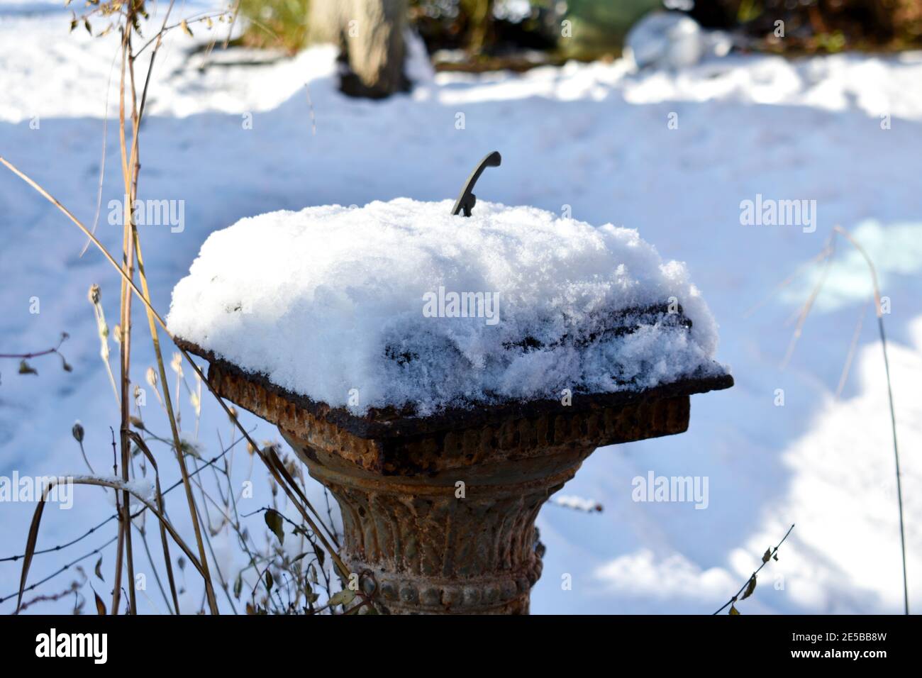 close up of rustic garden sun dial covered in deep snow on a sunny winters day Stock Photo