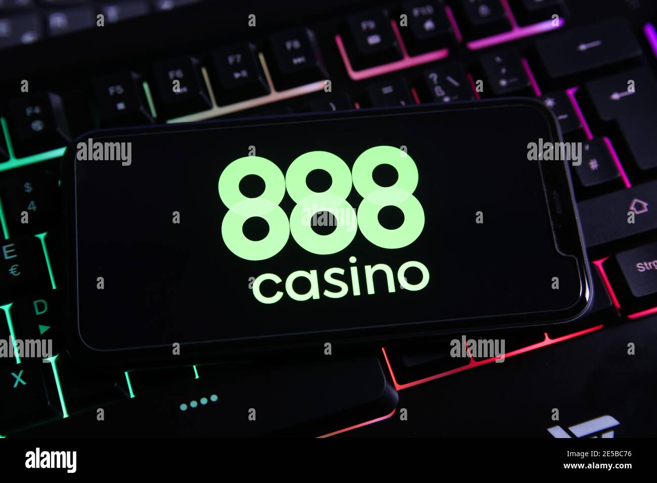 Viersen, Germany - January 9. 2021: Closeup of smartphone screen with logo lettering of online gamble provider 888 casino on illuminated keyboard (foc Stock Photo