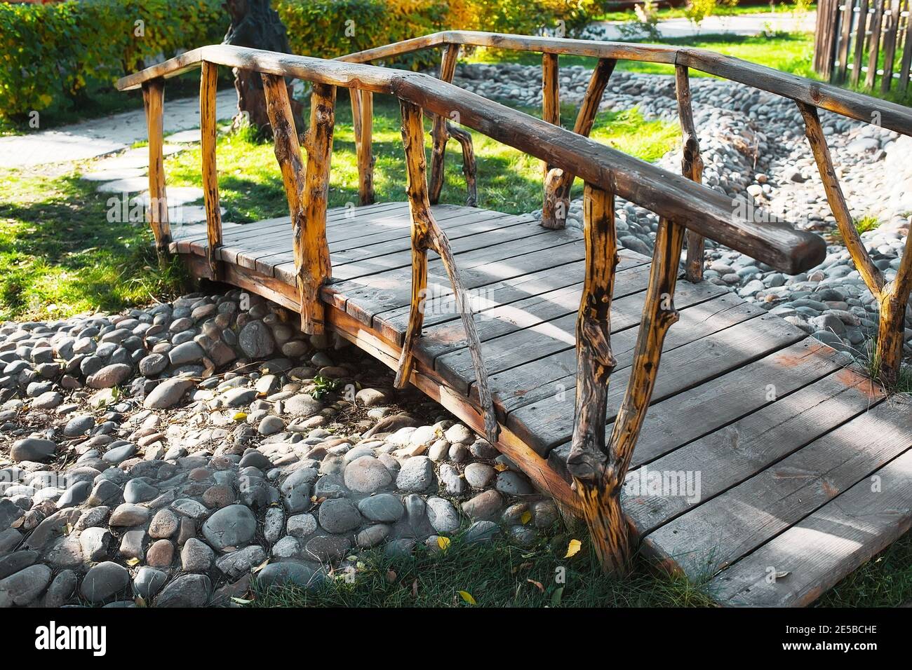 Vintage wooden bridge in a summer park across a dried-up stream.  Stock Photo