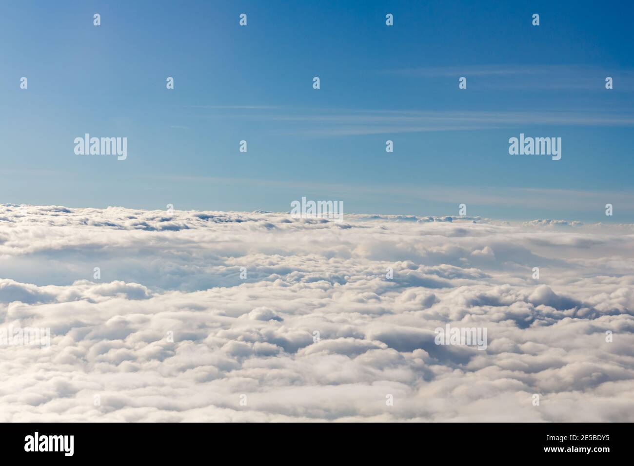 A view of the horizon formed above fluffy white clouds in the sky. Stock Photo