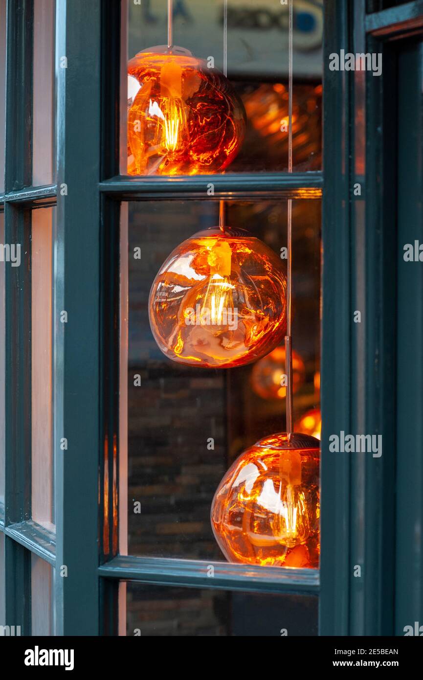 Spherical orange lamp shades hanging in a shop window Stock Photo