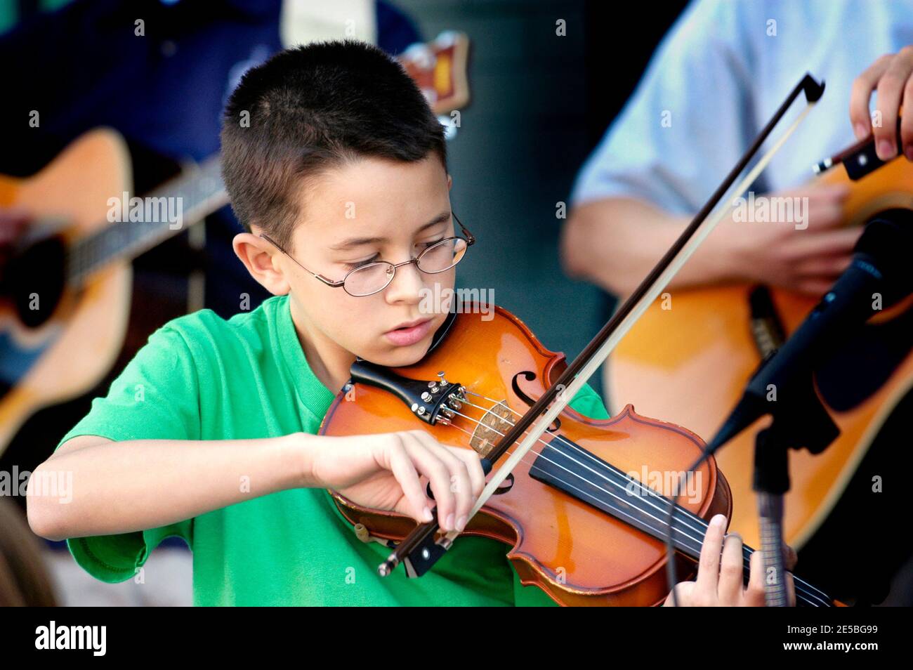 Violin strings group made up of children play a recital outside for the