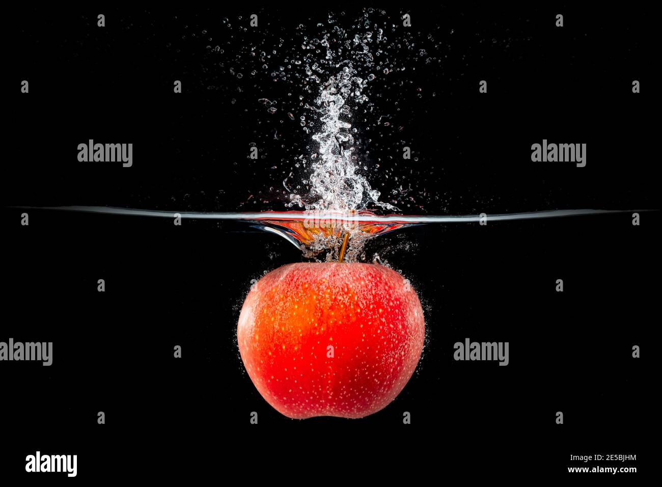red apple falling into splashing water Stock Photo