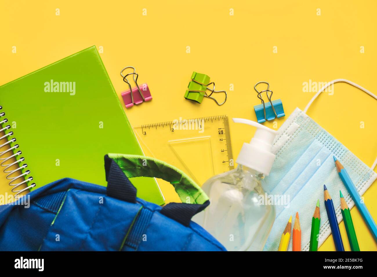 School supplies with medical mask and sanitizer bottle on yellow background.Selective focus Stock Photo