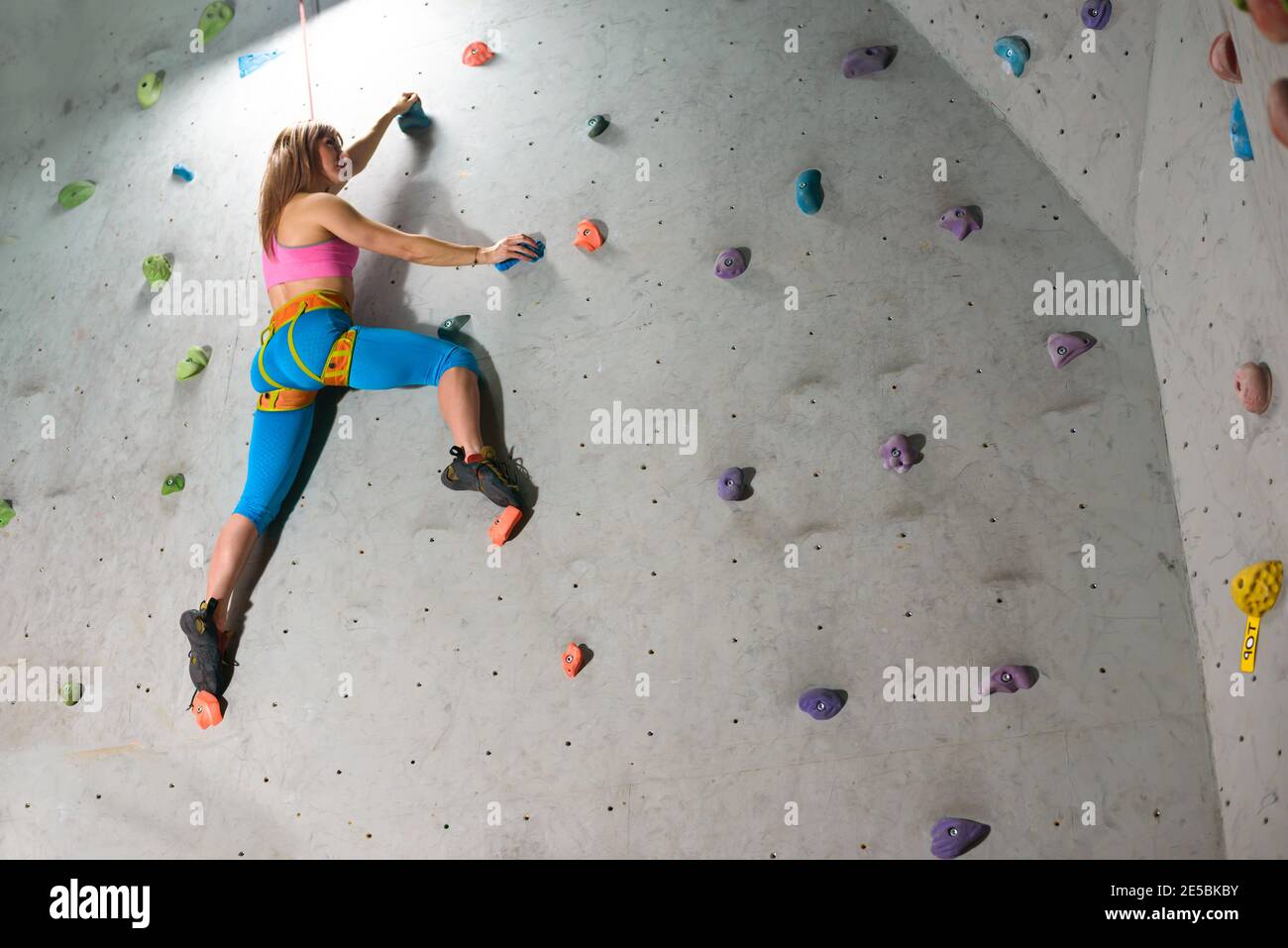 Beautiful Woman Climber Bouldering in the Climbing Gym. Extreme Sport and Indoor Climbing