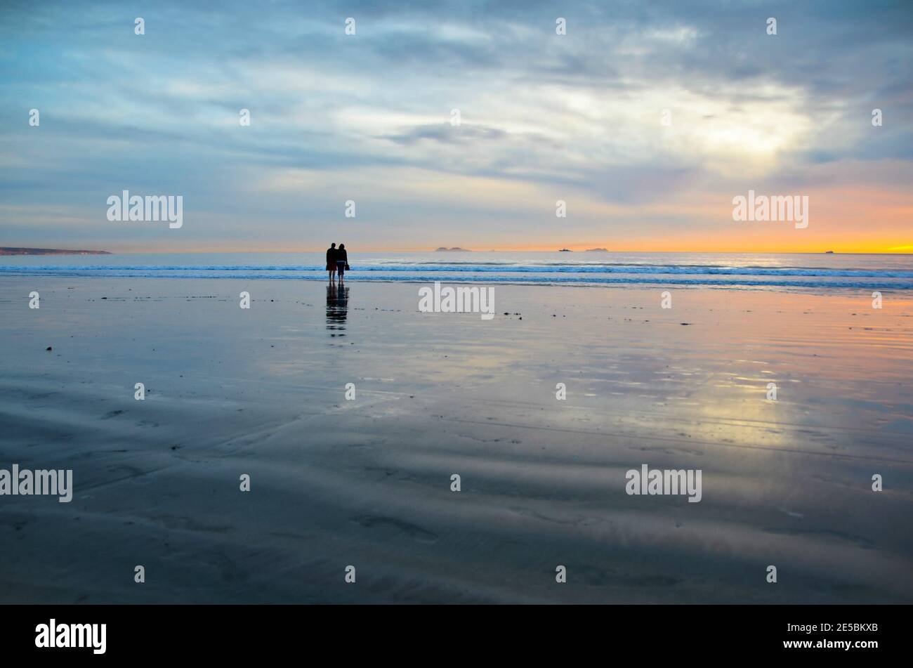 Young couple silhouettes on the Silver Strand Beach wet sand  watching the sunset at Coronado Island, San Diego Southern California USA. Stock Photo