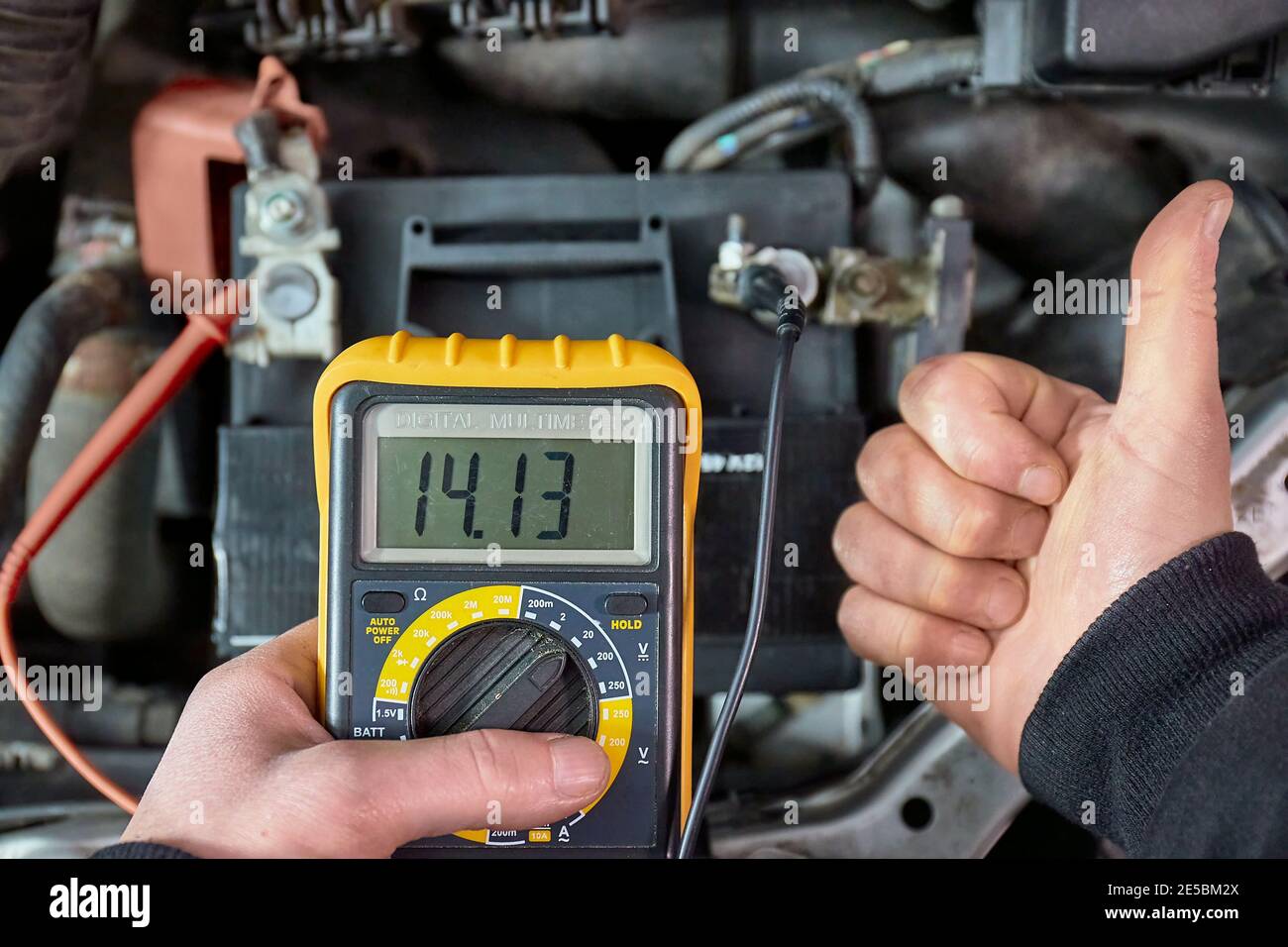 Checking car battery and alternator voltage with running engine Stock Photo