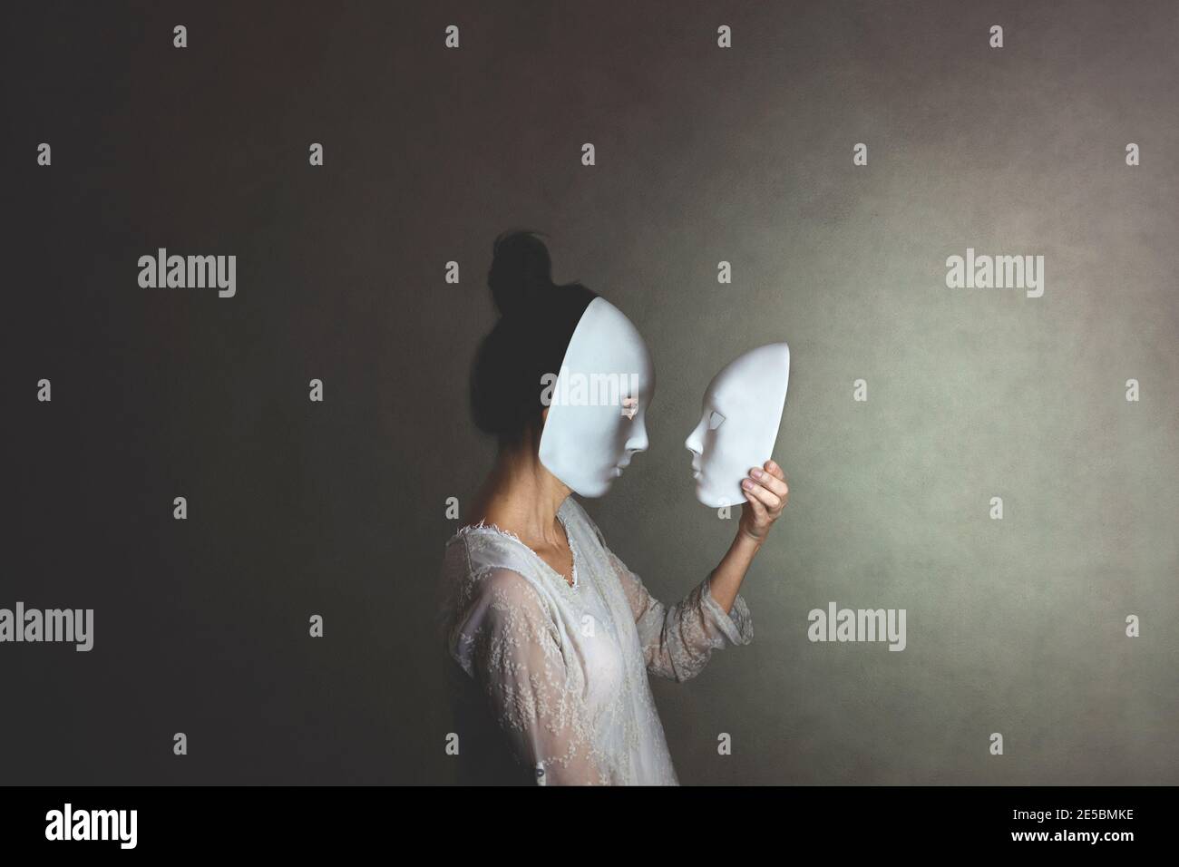 woman with mask looks at another mask of herself, concept of introspection Stock Photo