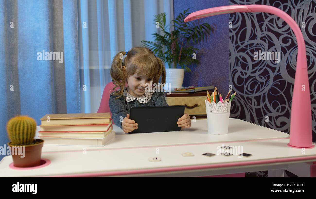 Doing Homework Using Technology Child girl doing school homework, using digital tablet computer at home ...