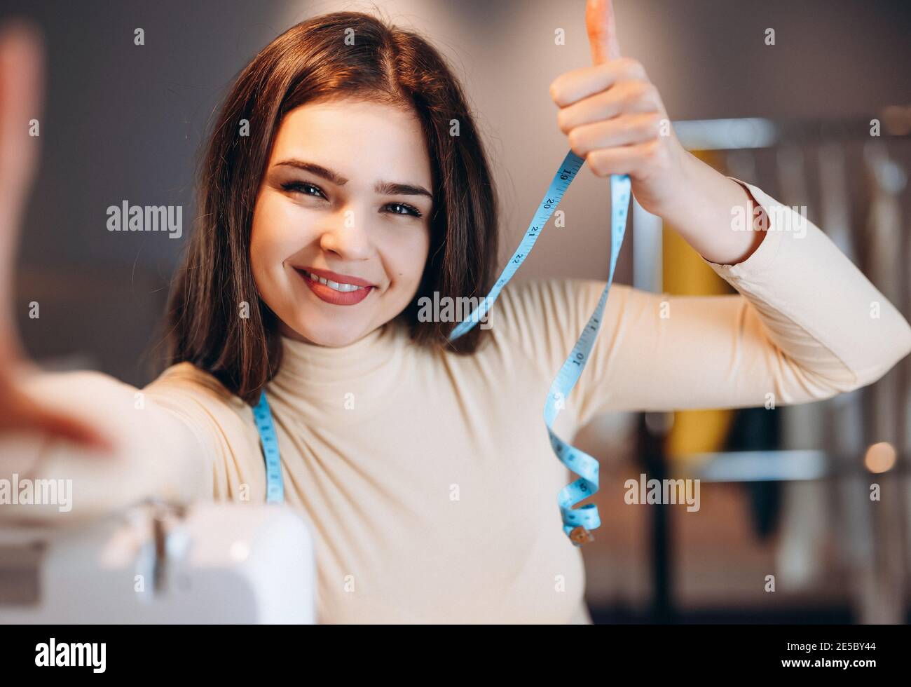 Young dressmaker woman taking selfie. Seamstress in workshop Stock Photo