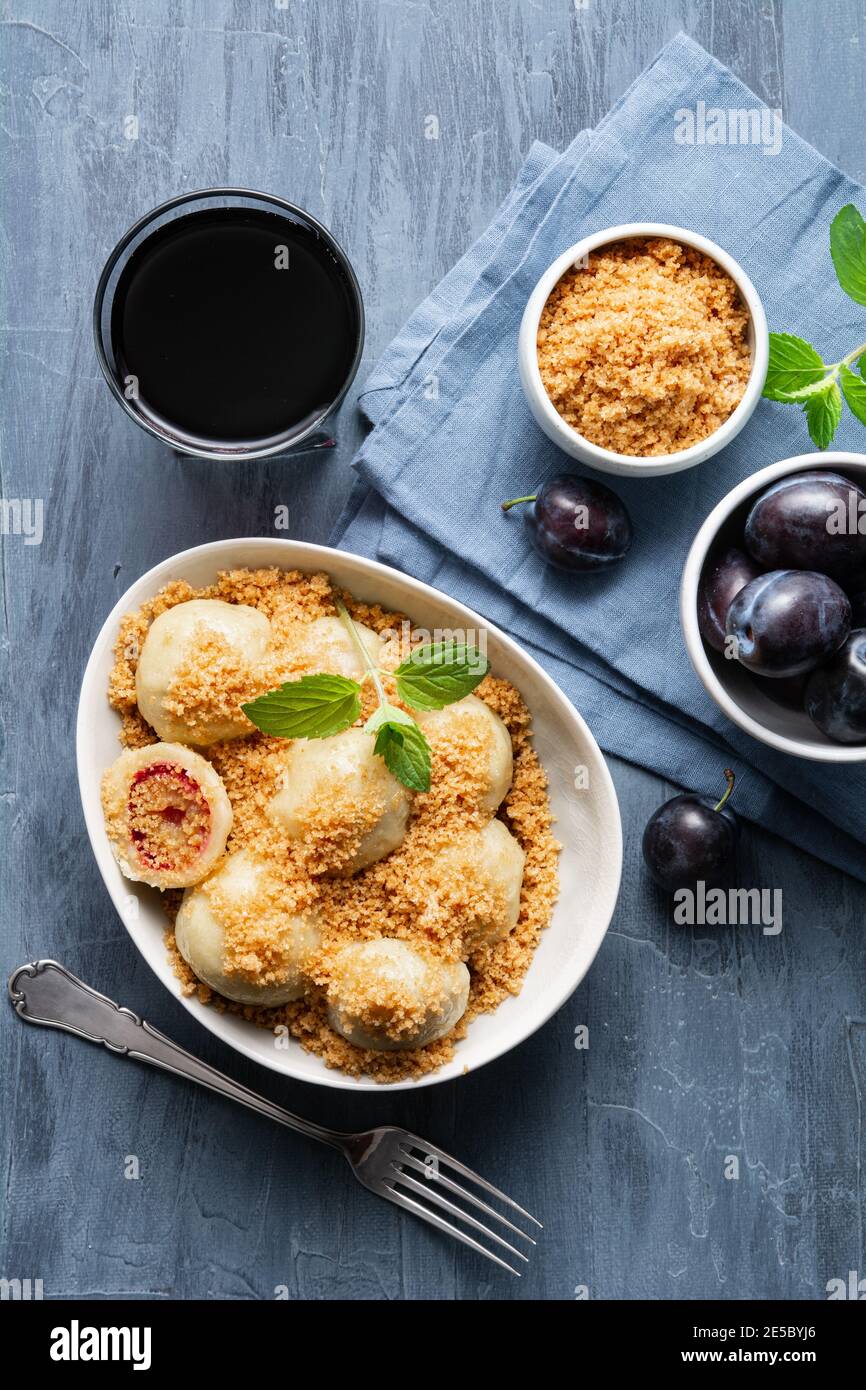 Freshly boiled plum dumplings topped with sweet toasted breadcrumbs in a bowl, served with black currant juice Stock Photo