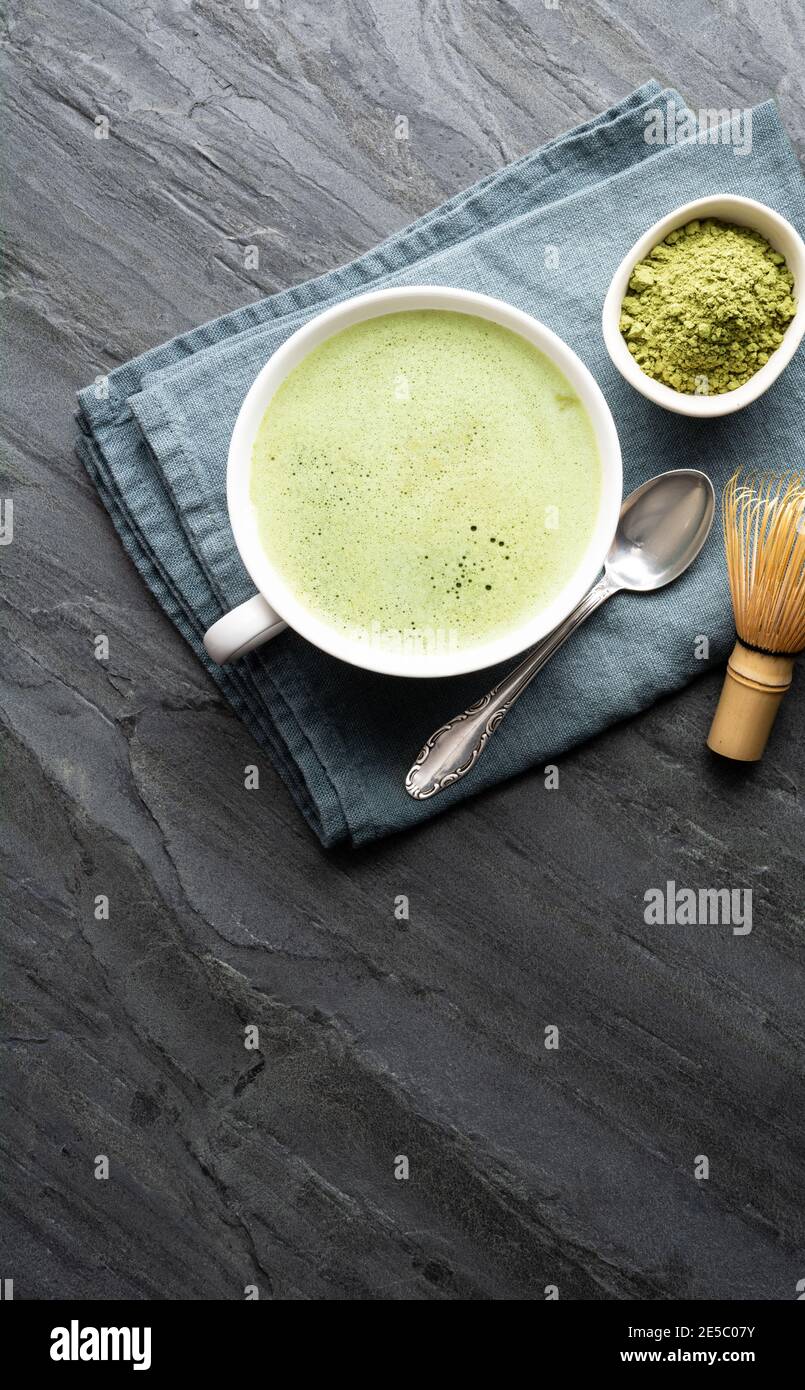A cup of fresh frothy Matcha green tea decorated with bamboo whisk on a stone background with copy space Stock Photo