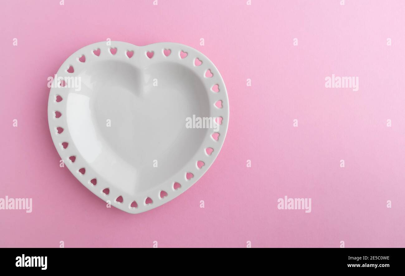Heart shaped porcelain plate on a pink background with space for text ...