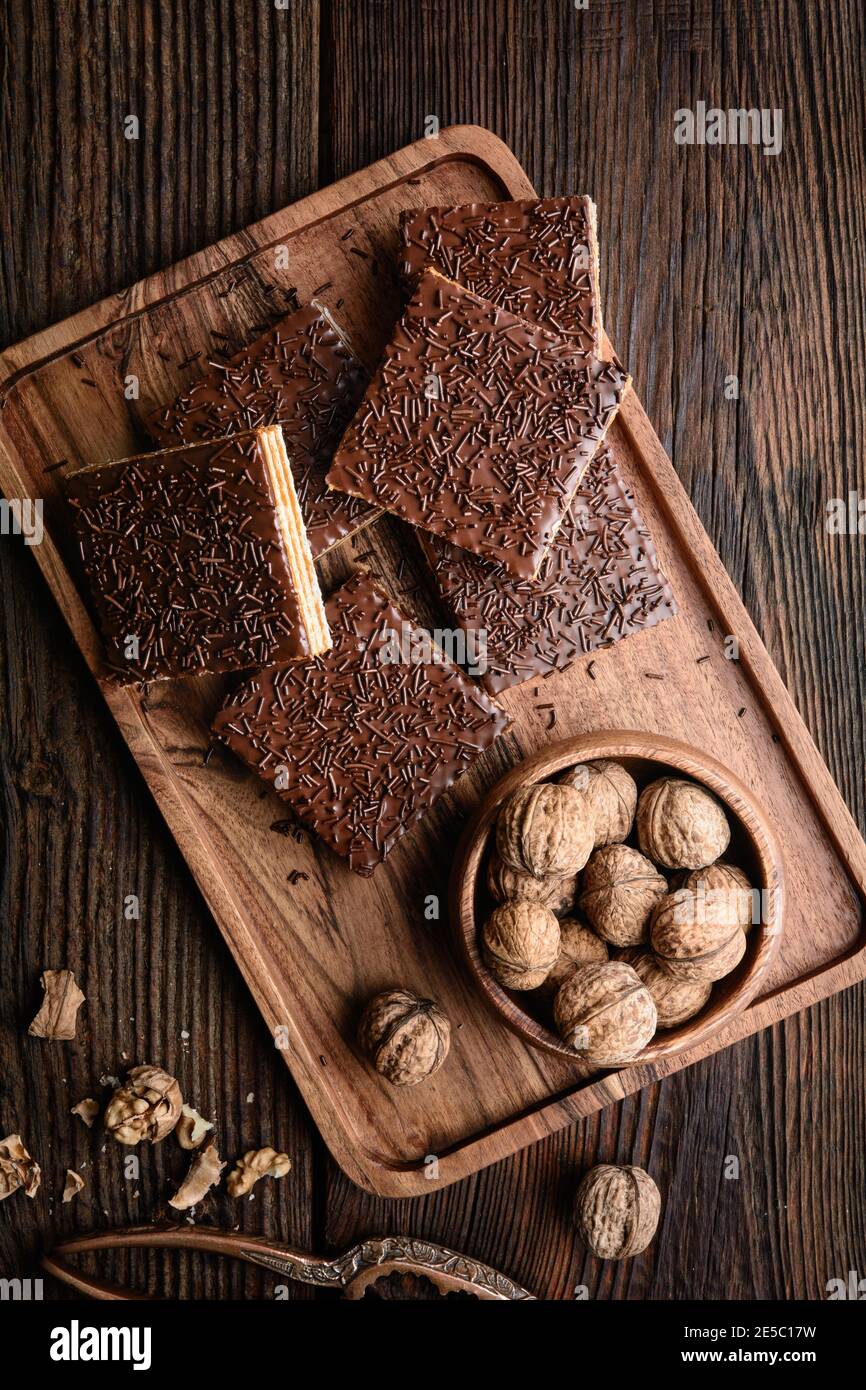Homemade sweet wafer filled with walnut toffee filling and topped with chocolate frosting on wooden background Stock Photo