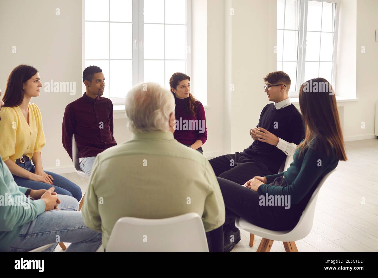 Diverse patients sitting in circle and listening to therapist in group therapy meeting Stock Photo
