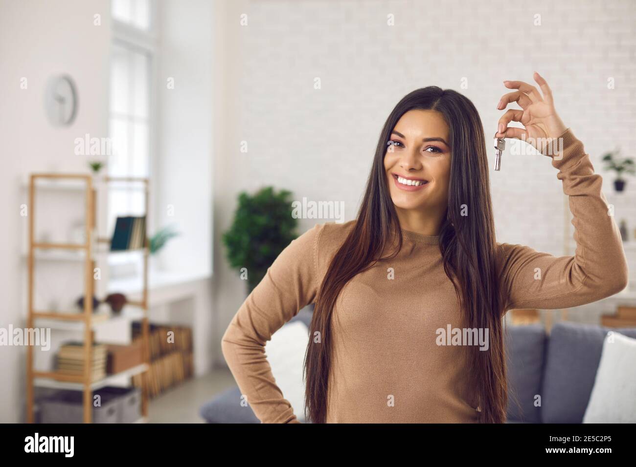 Happy young woman holding keys to her new house or apartment and ...
