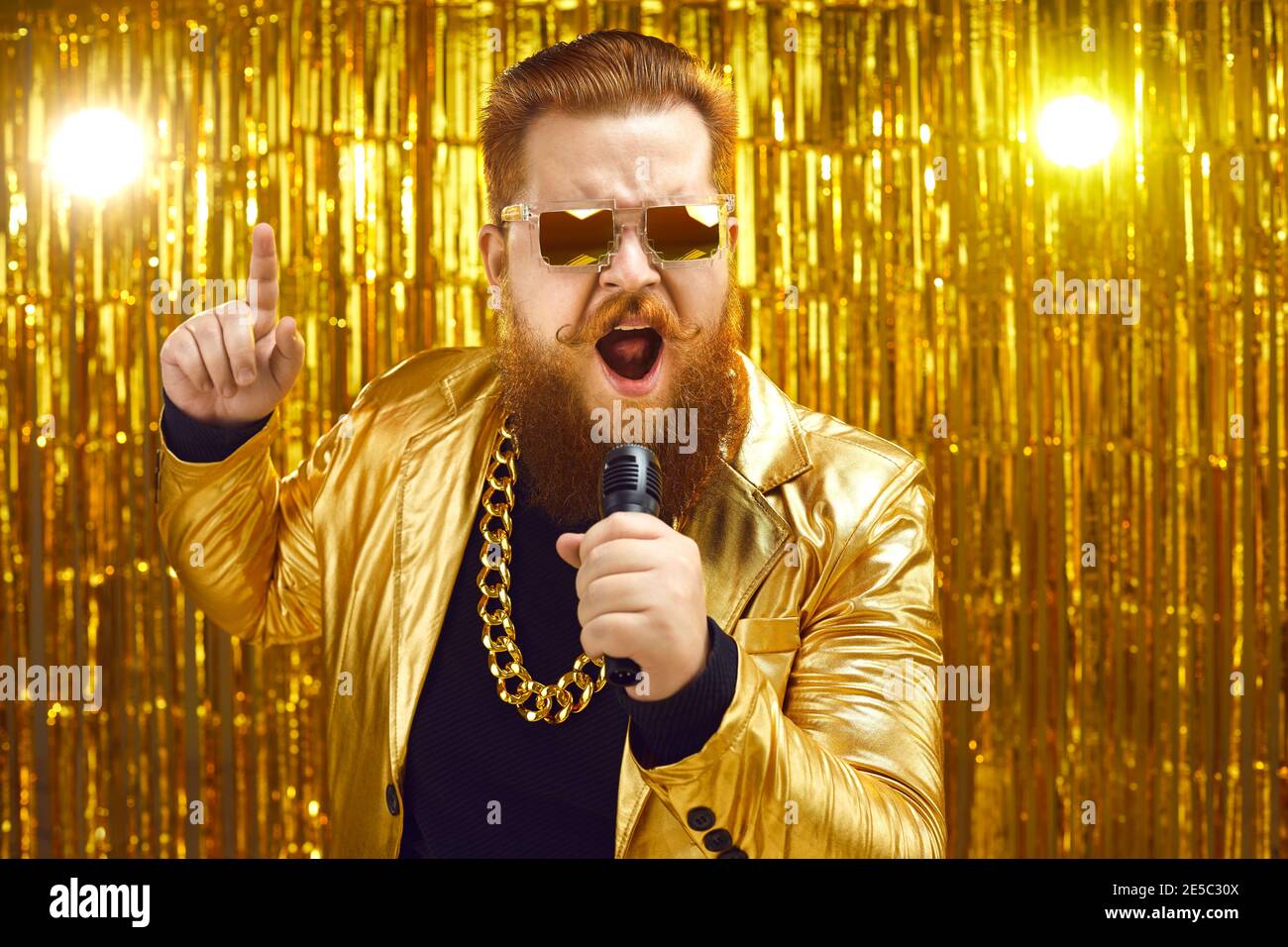 Singer in golden jacket and gold chain holding mic and singing songs at retro music concert Stock Photo