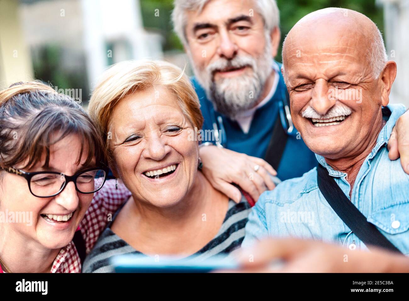 Happy senior friends taking selfie around old town street - Retired people having fun together with mobile phone - Positive elderly lifestyle concept Stock Photo