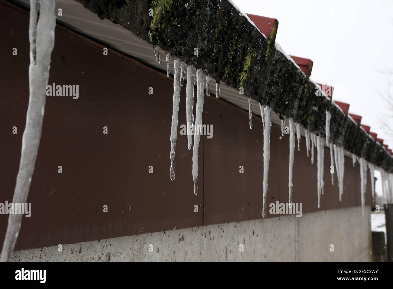 The snow on the roof melts and forms ice icicles. Stock Photo