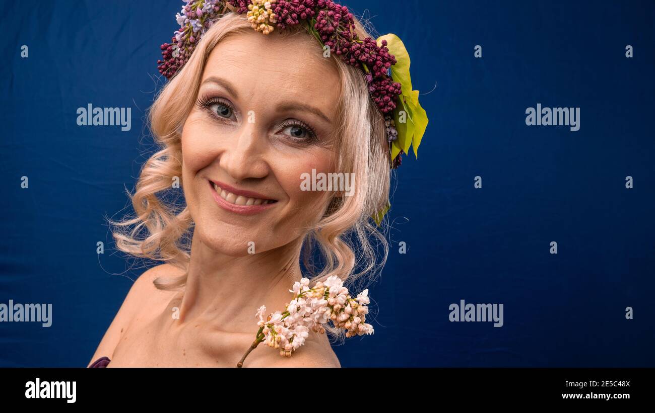 Blessed young woman in a lilac wreath with a kind look overjoyed, with a day Stock Photo