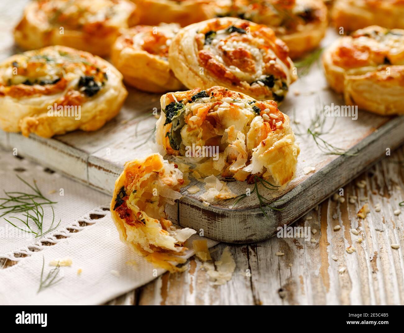 Puff Pastry appetizers Pinwheels stuffed with salmon, cheese and spinach on wooden board close-up Stock Photo