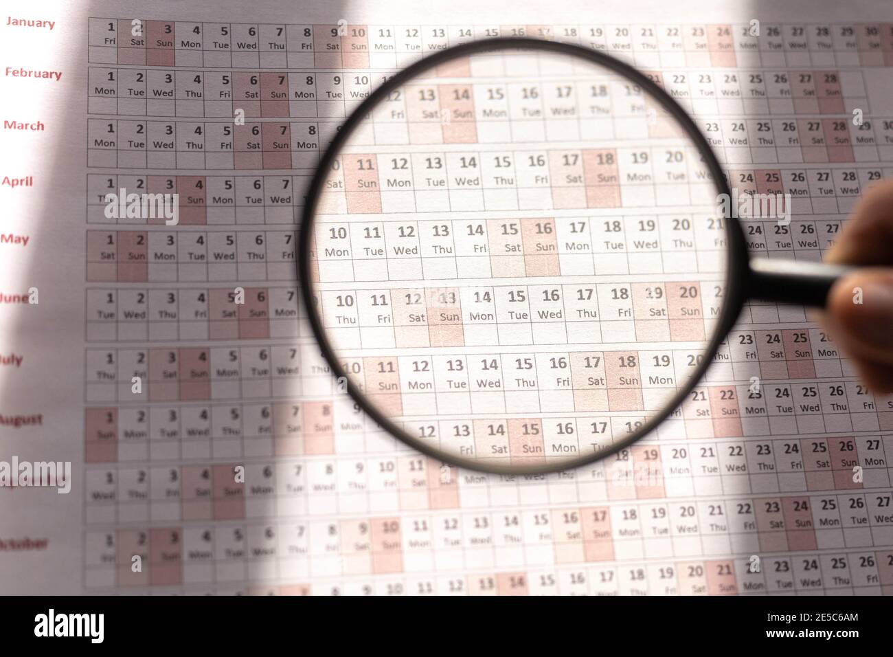 selective focus of the analysis and collection of data in an agenda or planner to organize the tasks to be performed examined with a magnifying glass Stock Photo