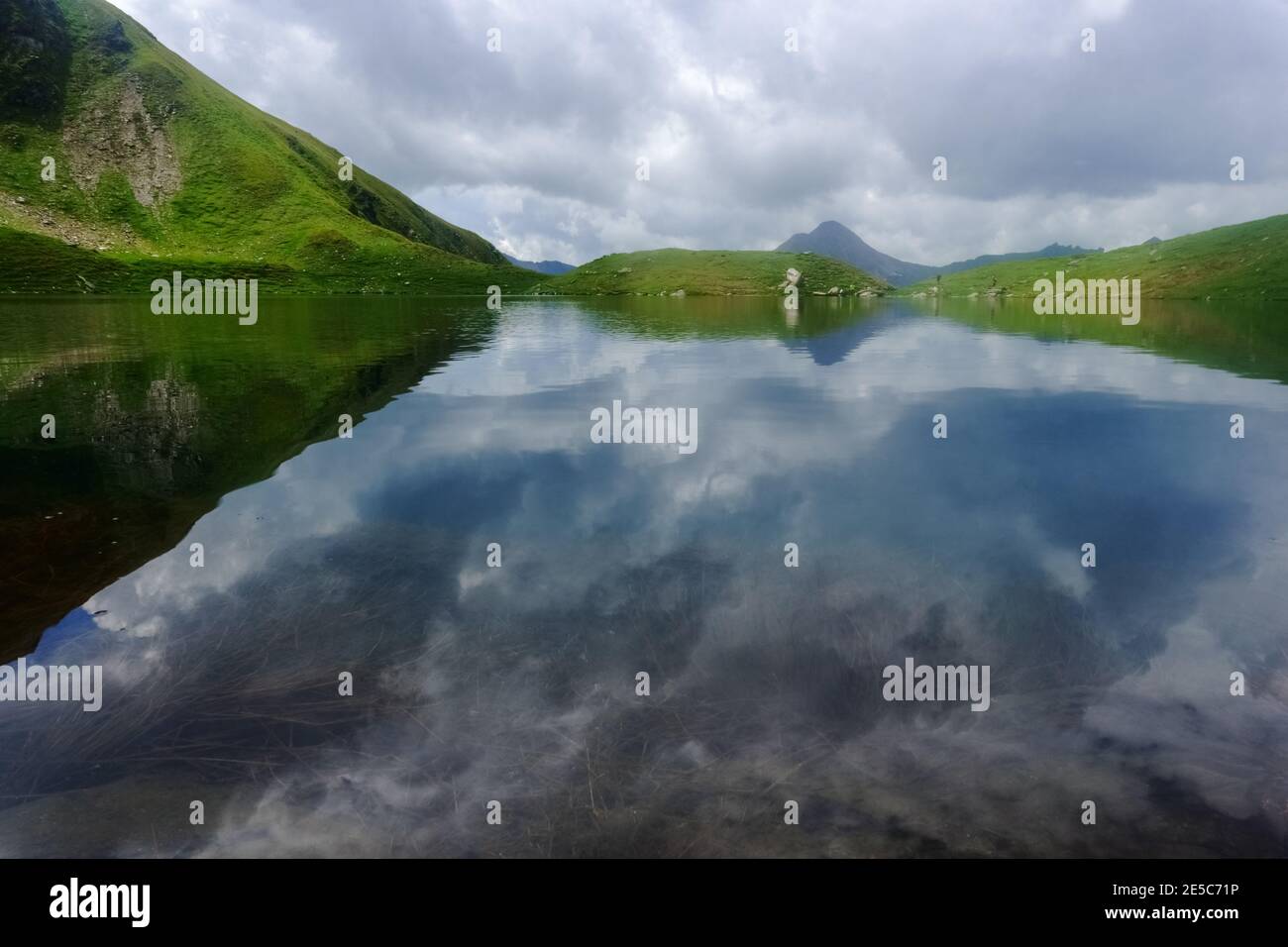 reflection in a mountain lake in green hills while hiking on vacation Stock Photo