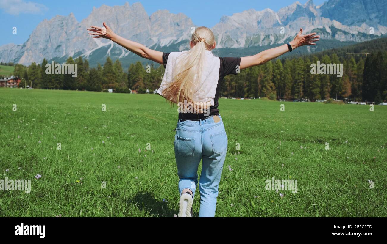Back View Of Woman Running On The Field With Mountains In Front