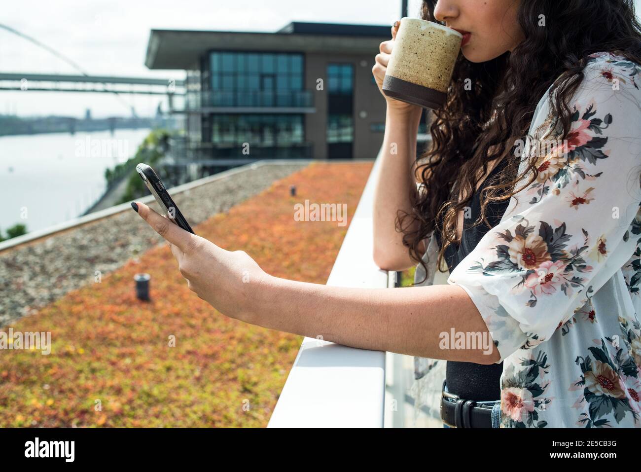 Close up of woman holding phone and sipping from coffee cup Stock Photo