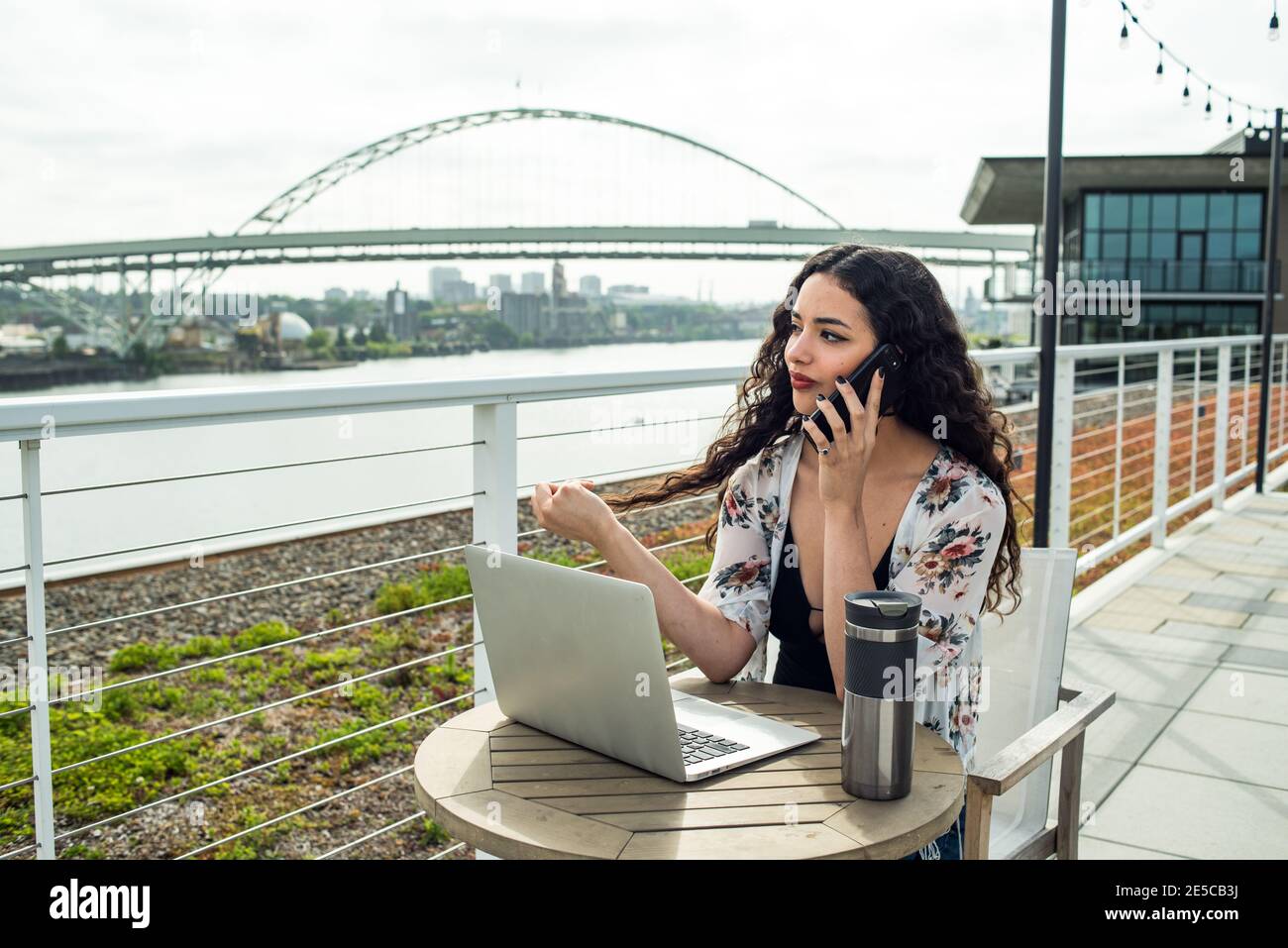 Woman sitting on rooftop with laptop talking on phone Stock Photo