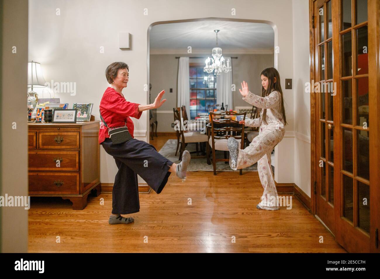 A grandmother teaches her tween granddaughter tai chi at home Stock Photo