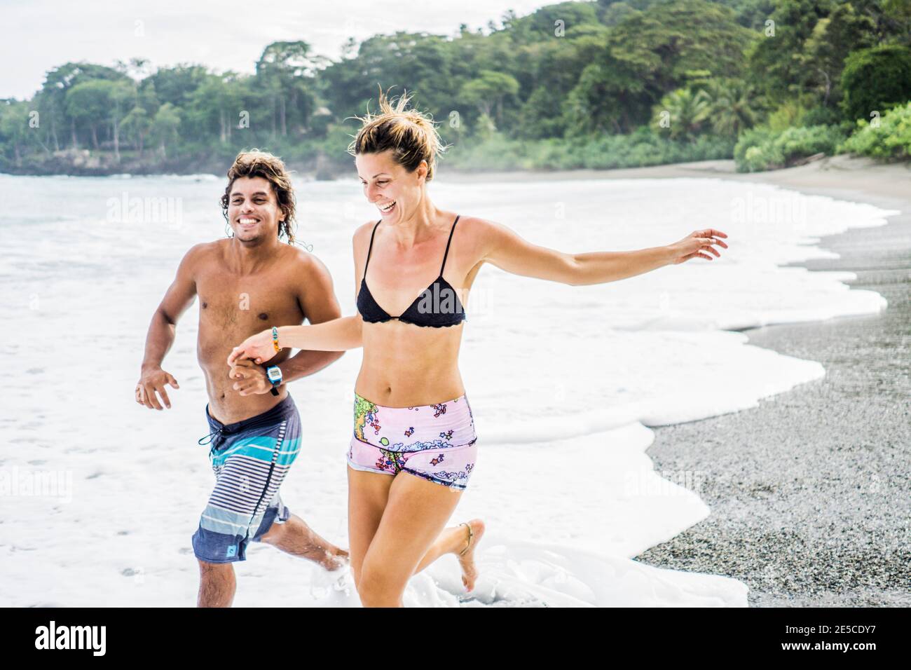 Multi ethnic couple on costa rican vacation running on beach, Matapalo, Puerto jimenez, costa rica, central america Stock Photo