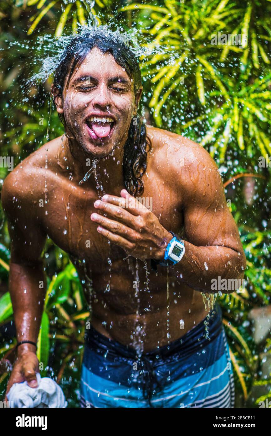 Surfer making funny face in jungle shower, Costa rica, Central America