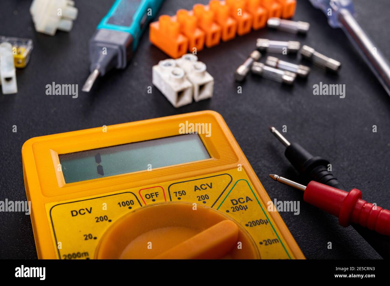 A meter for electrical measurements on a workbench. Accessories for repair and installation of electrical equipment. Dark background. Stock Photo