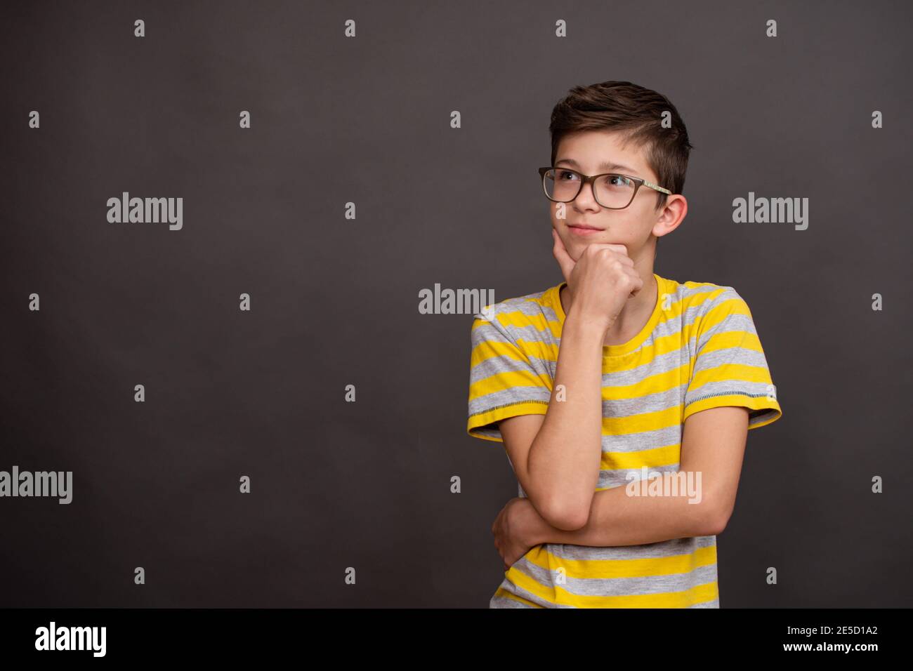 A teenage boy with glasses thought about it. Serious face expression.  Stock Photo