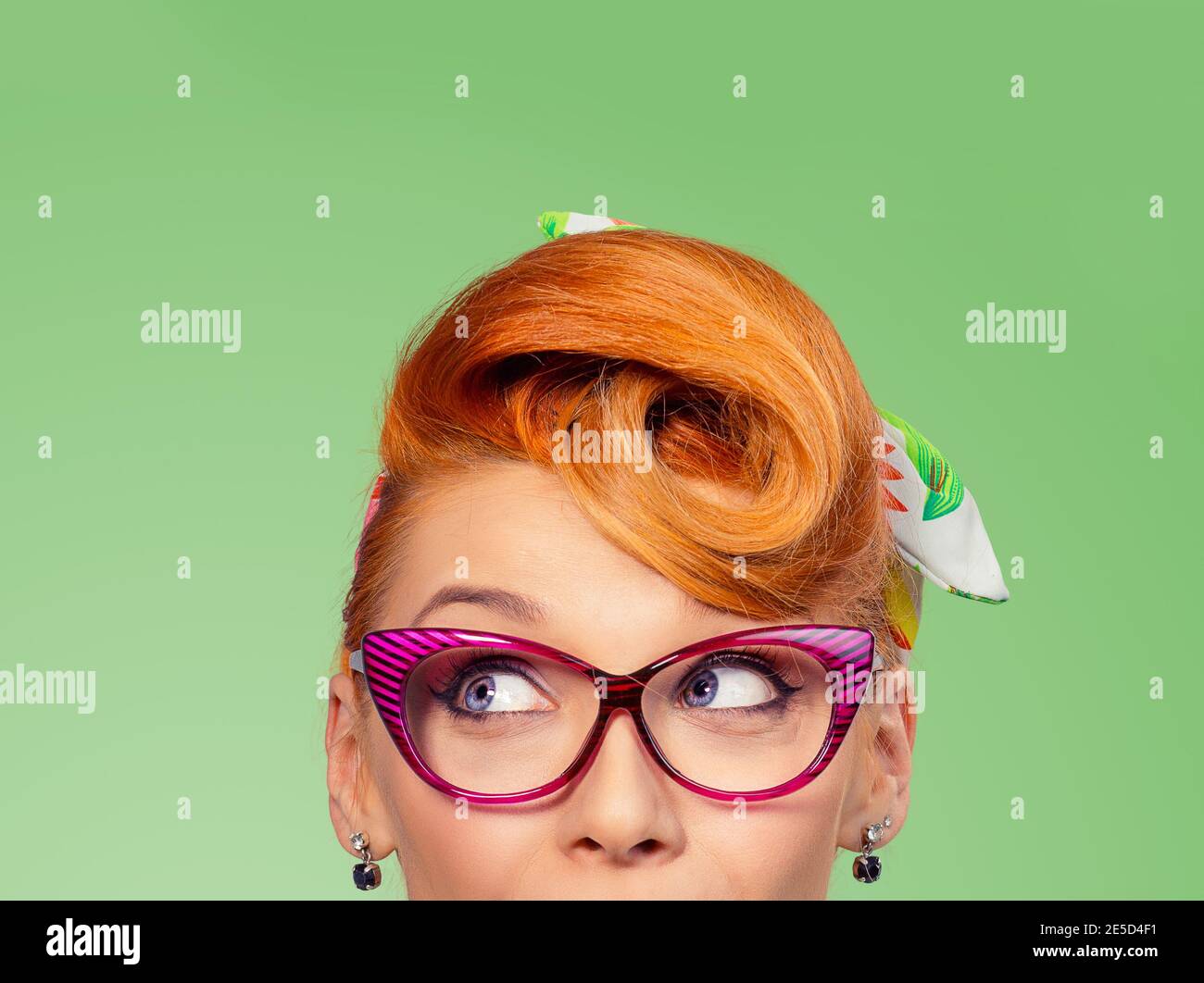 Wow, Look here aside. Closeup red head young woman pretty amazed pinup girlexcited surprised shocked looking up to side retro vintage 50s hairstyle on Stock Photo