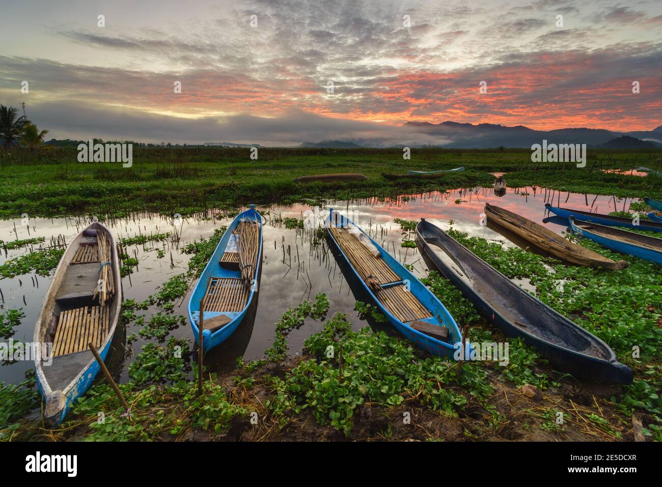 Row of Fishing boats moored on Lebo lake at sunset, Sumbawa, Indonesia Stock Photo