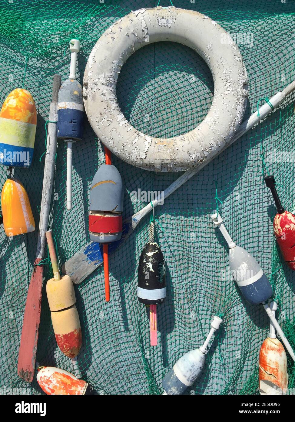 Life saver, oars and fishing buoys hanging on a fishing net, USA Stock Photo