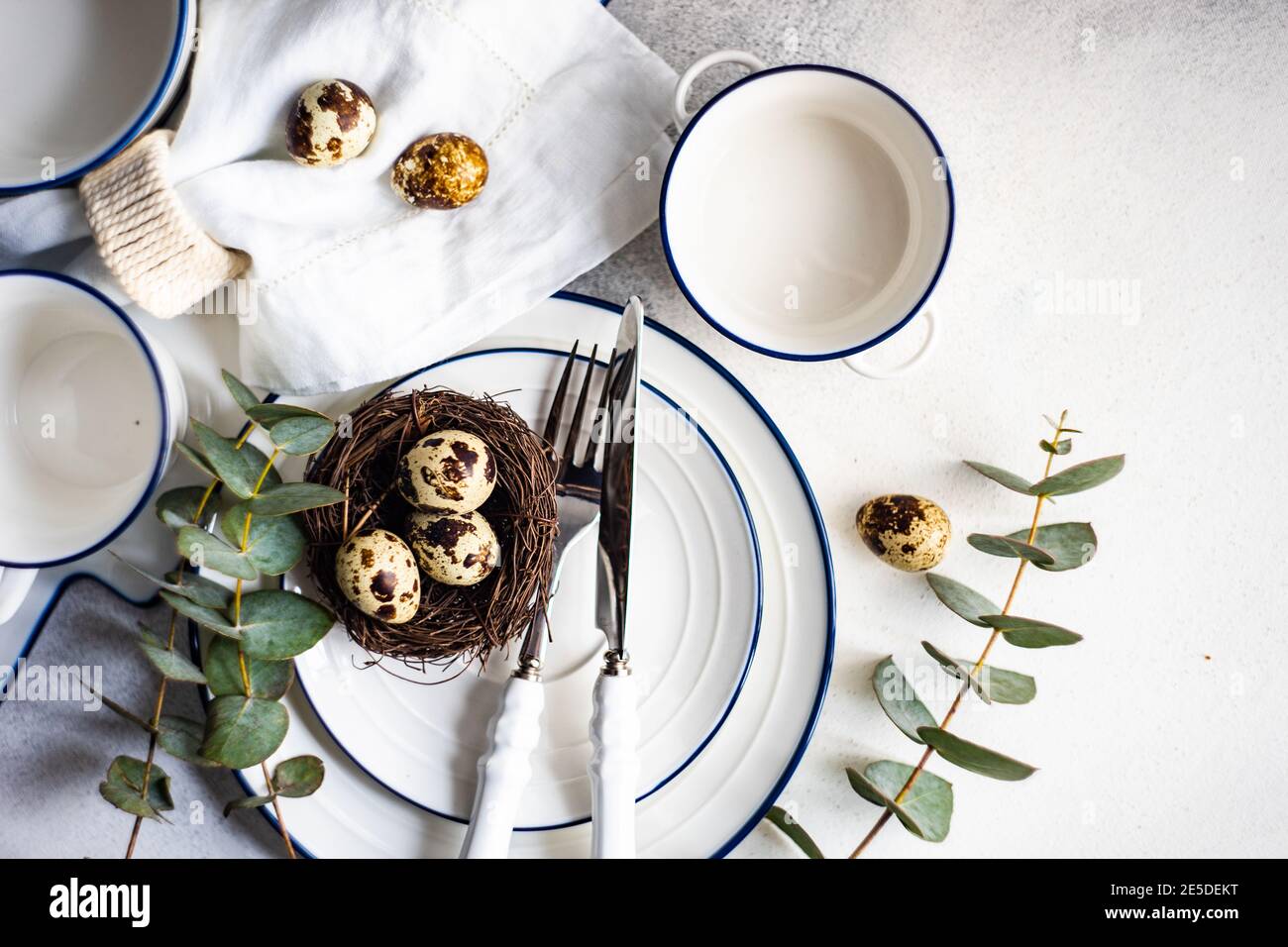 Easter table setting with Easter eggs in a bird's nest and eucalyptus stems Stock Photo